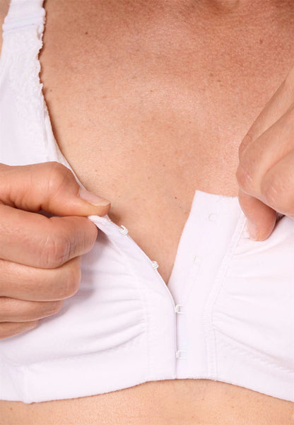 Person adjusting a white bra with a close-up on the chest area.