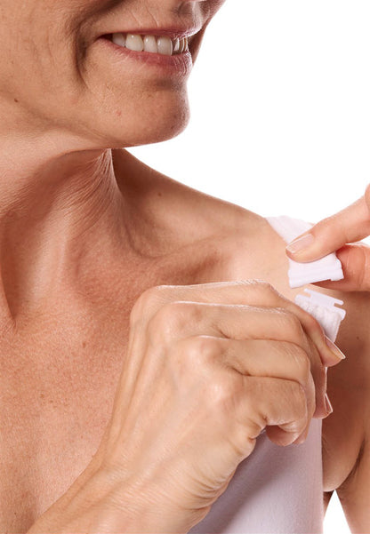 Woman applying a transparent patch to her shoulder against a white background