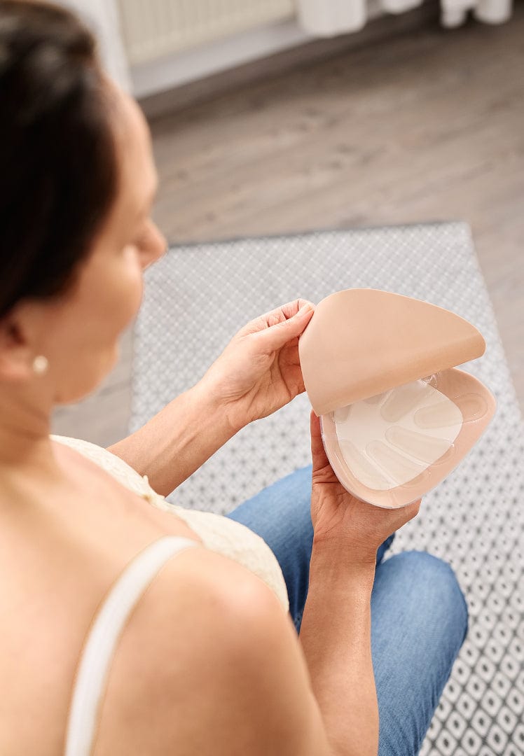 Woman holding a custom breast form with a cooling lining on a neutral background