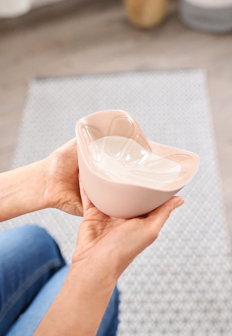 Person holding a custom breast form  on a neutral background